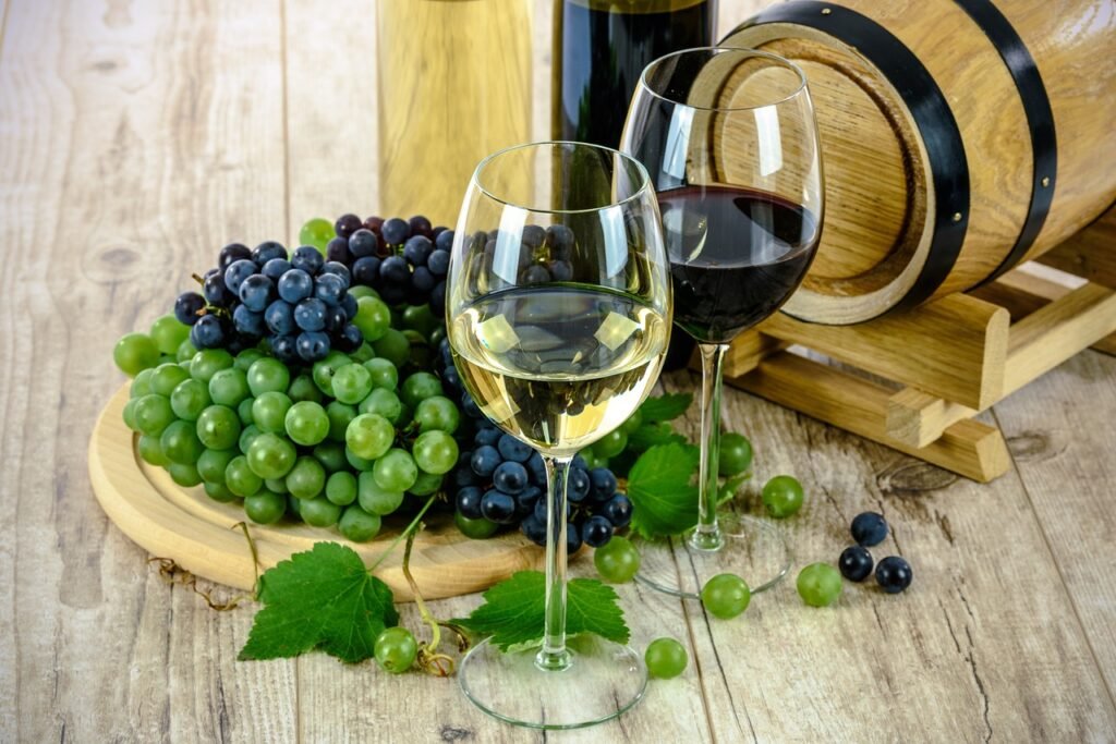 Red and white wine glasses with grapes and a barrell